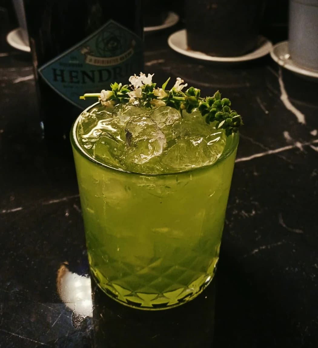 A green cocktail garnished with fresh flowers
