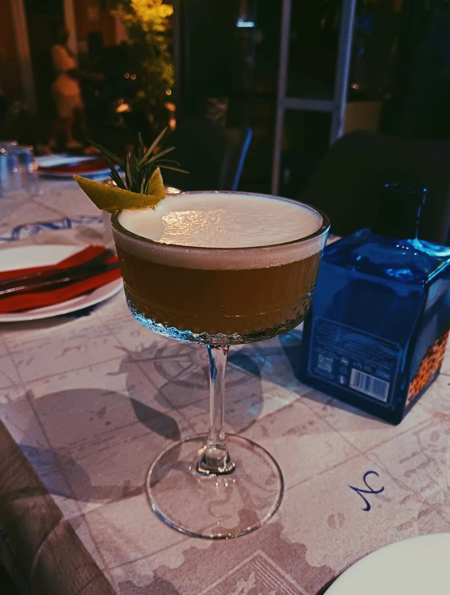 A cocktail on the table, menu in the background