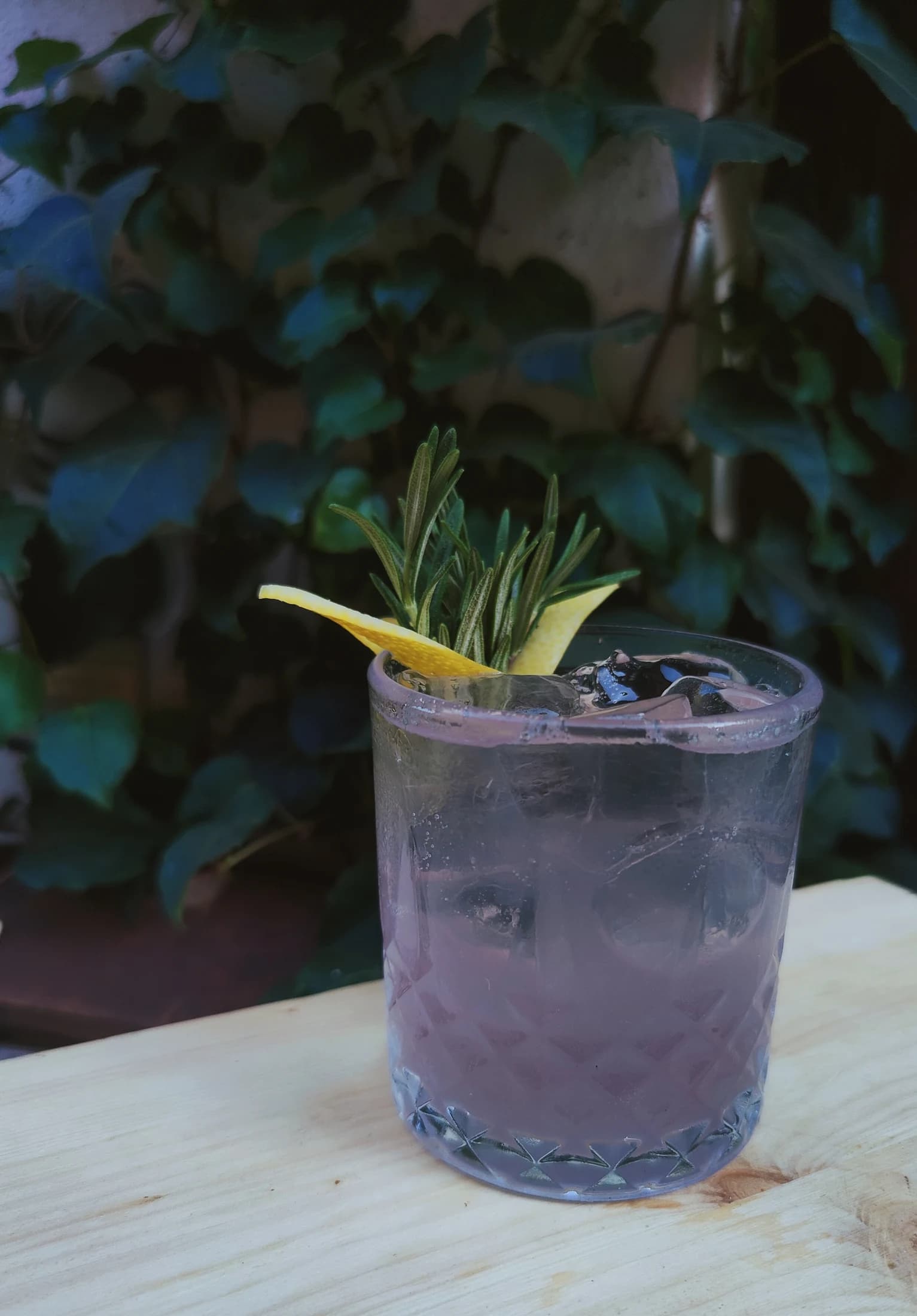 A lavender-hued cocktail garnished with rosemary