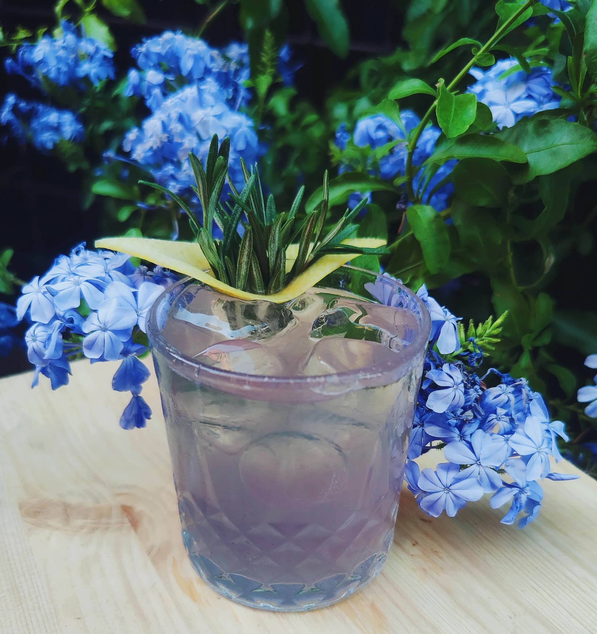 A lavender cocktail set among fresh flowers