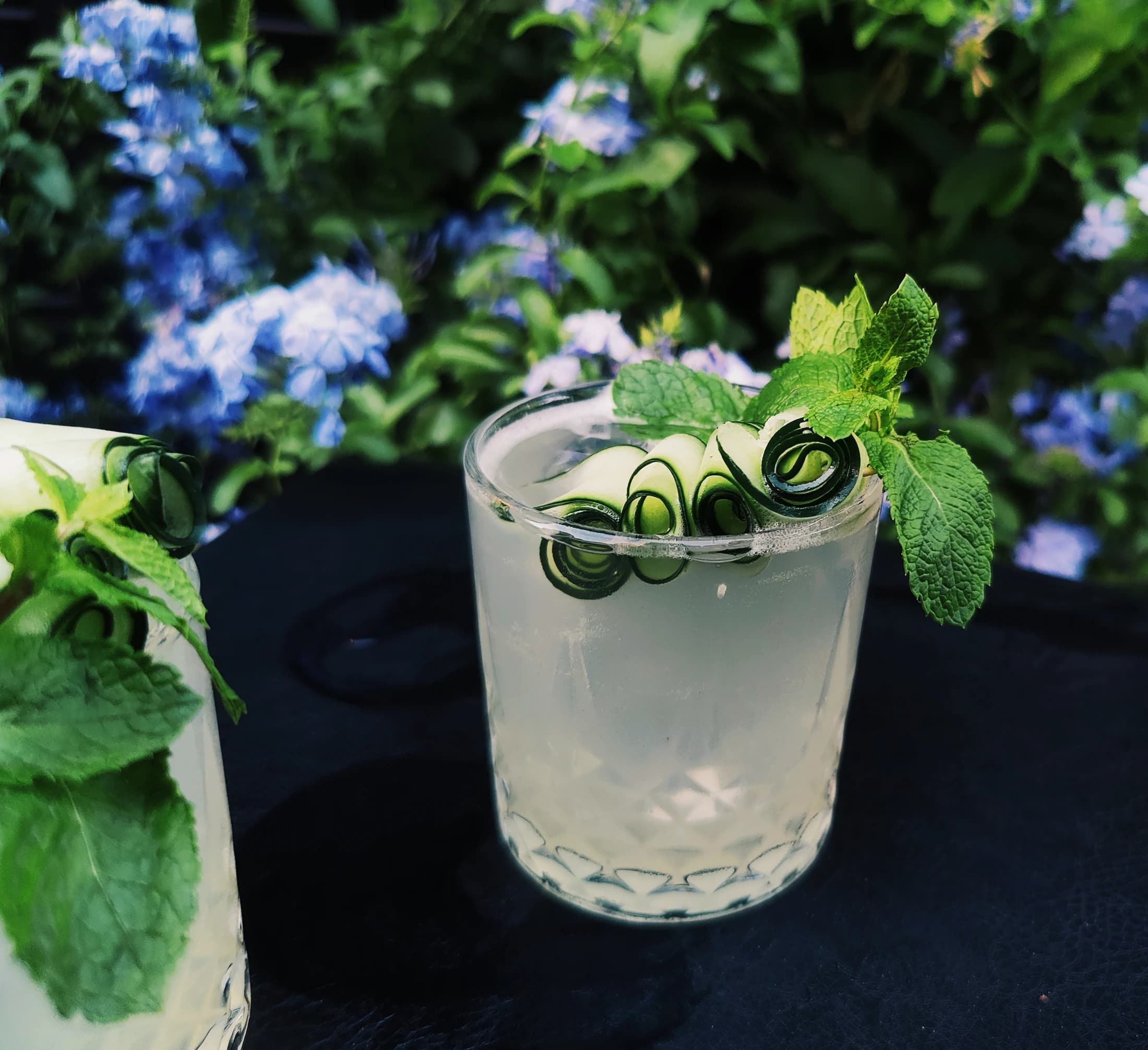 A cocktail with cucumber ribbons among hydrangeas