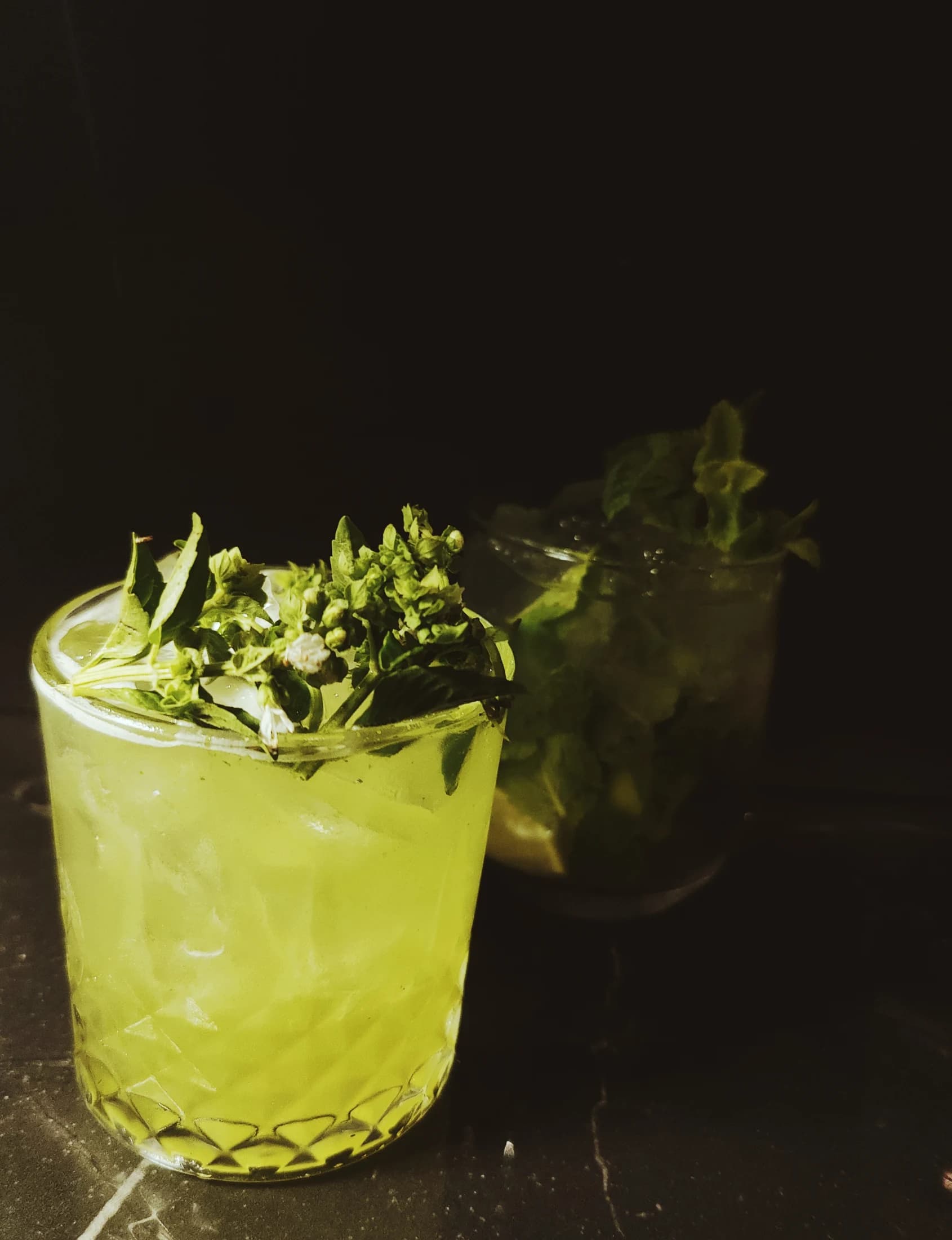 A yellow-green cocktail with fresh herbs