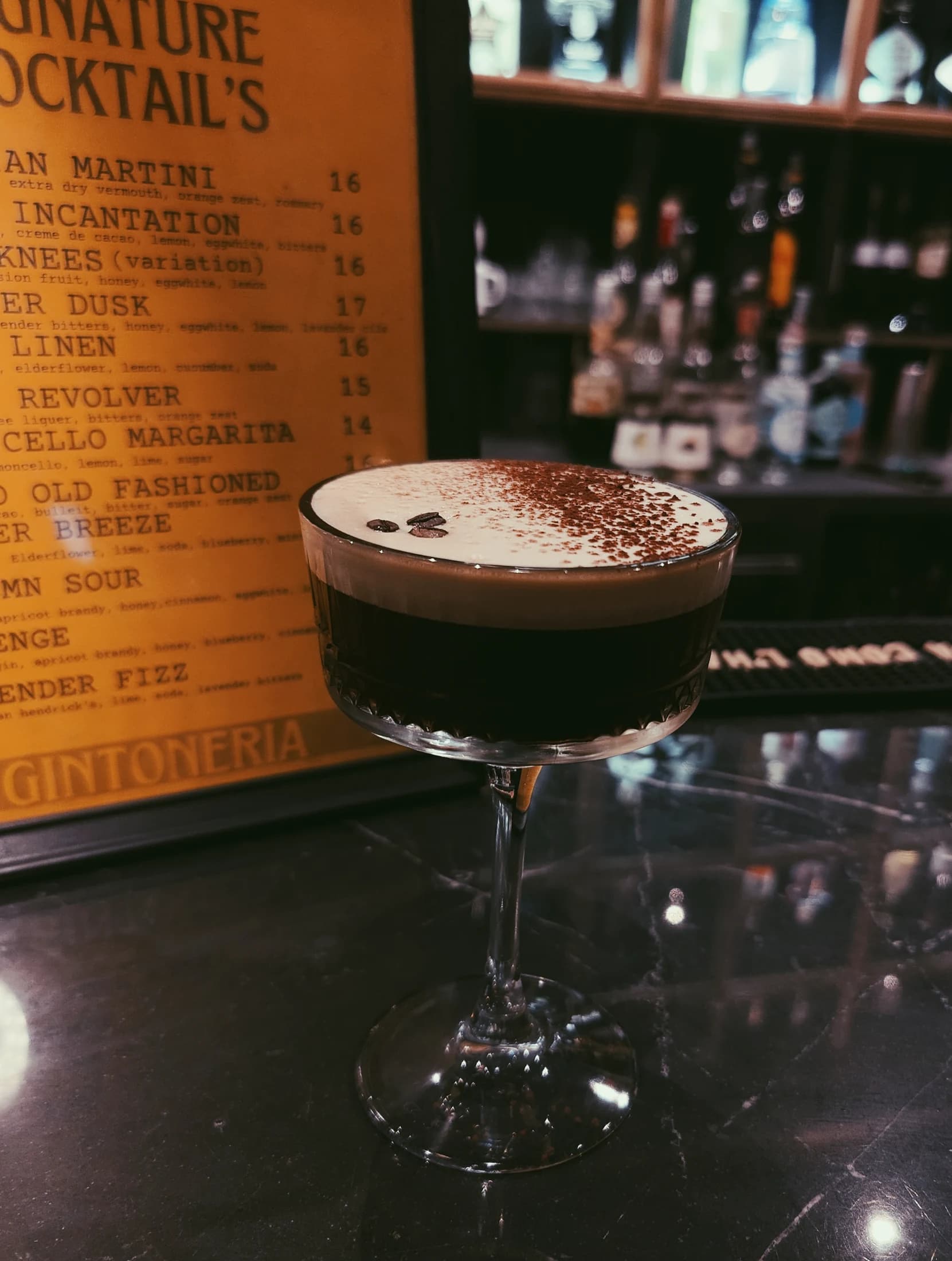 An espresso martini at the bar, cocktail menu behind it