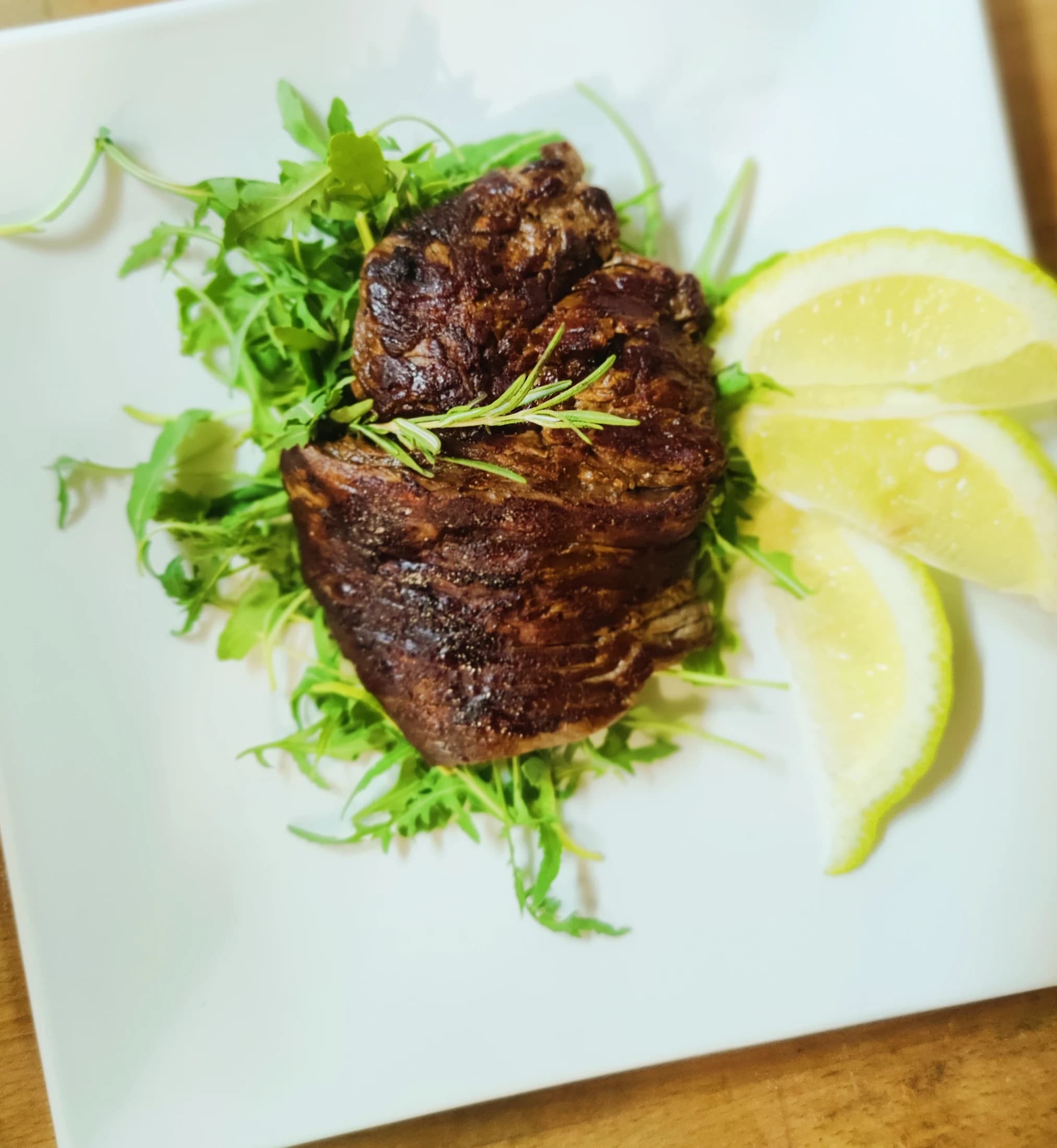 A grilled steak with arugula and lemon