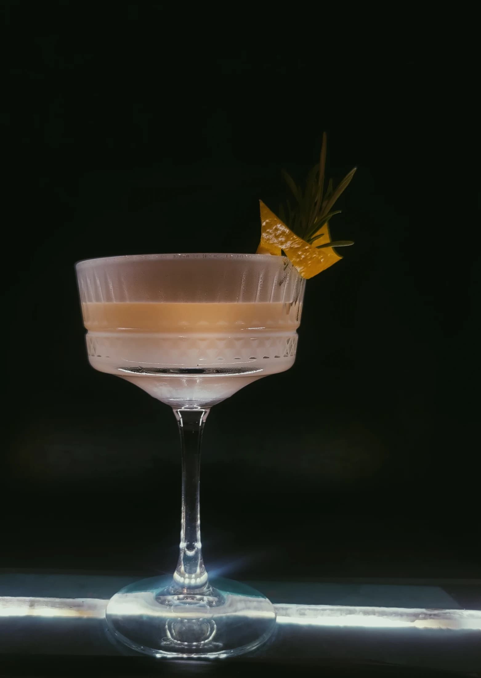 A pink sour cocktail with a dried citrus garnish