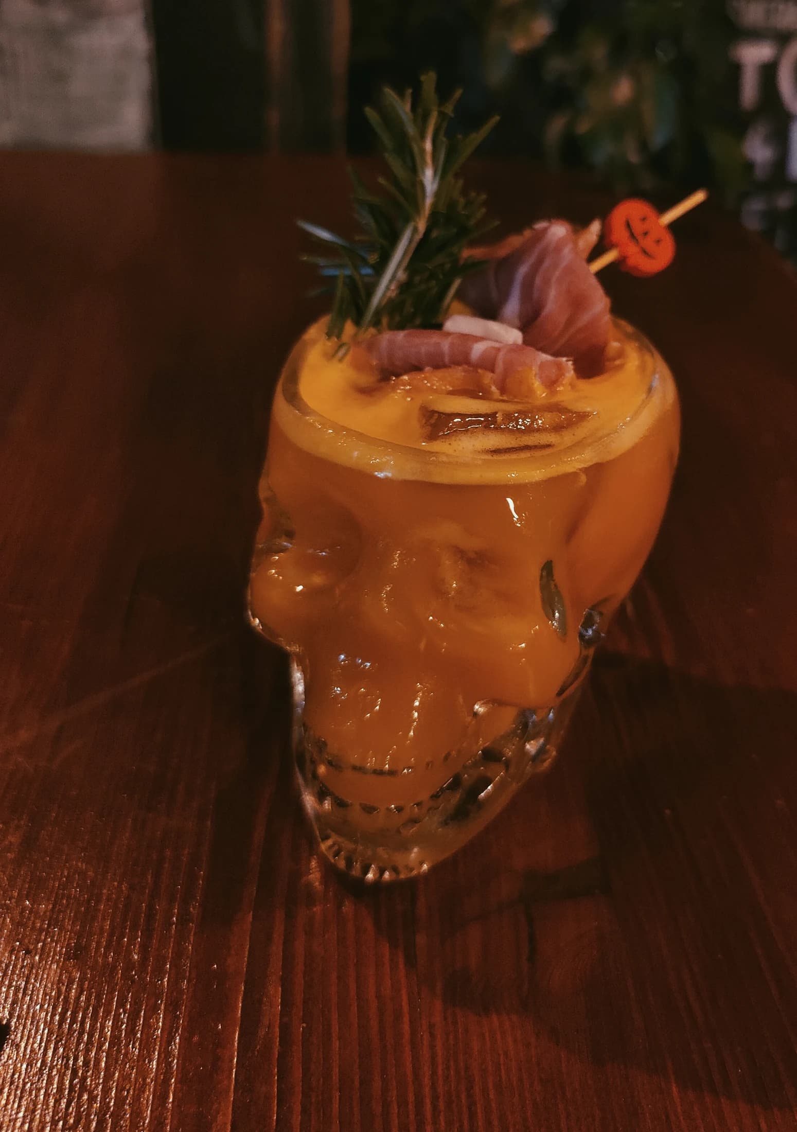 An orange cocktail served in a crystal skull glass