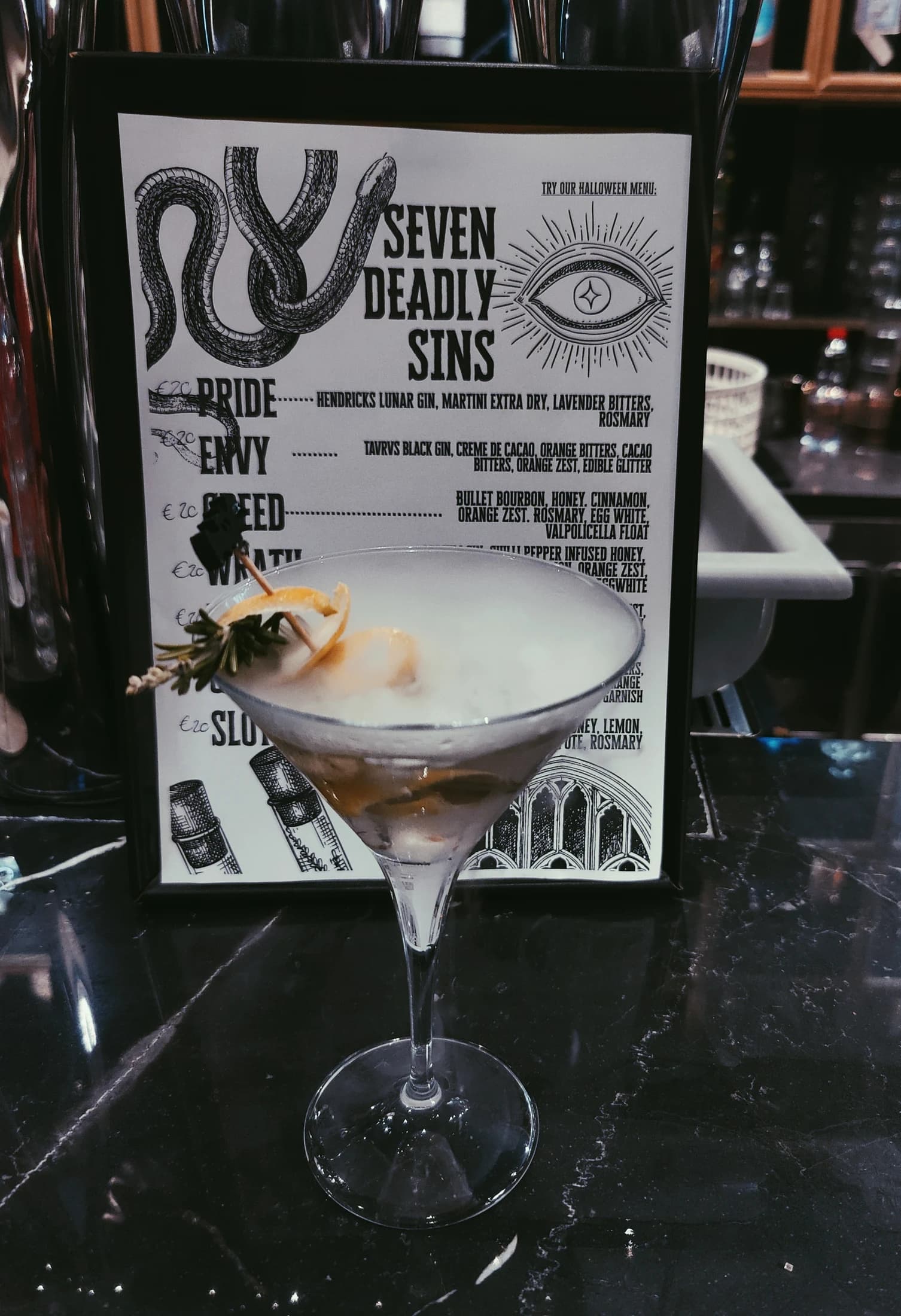 A cocktail beside the bar's 'Seven Deadly Sins' menu board