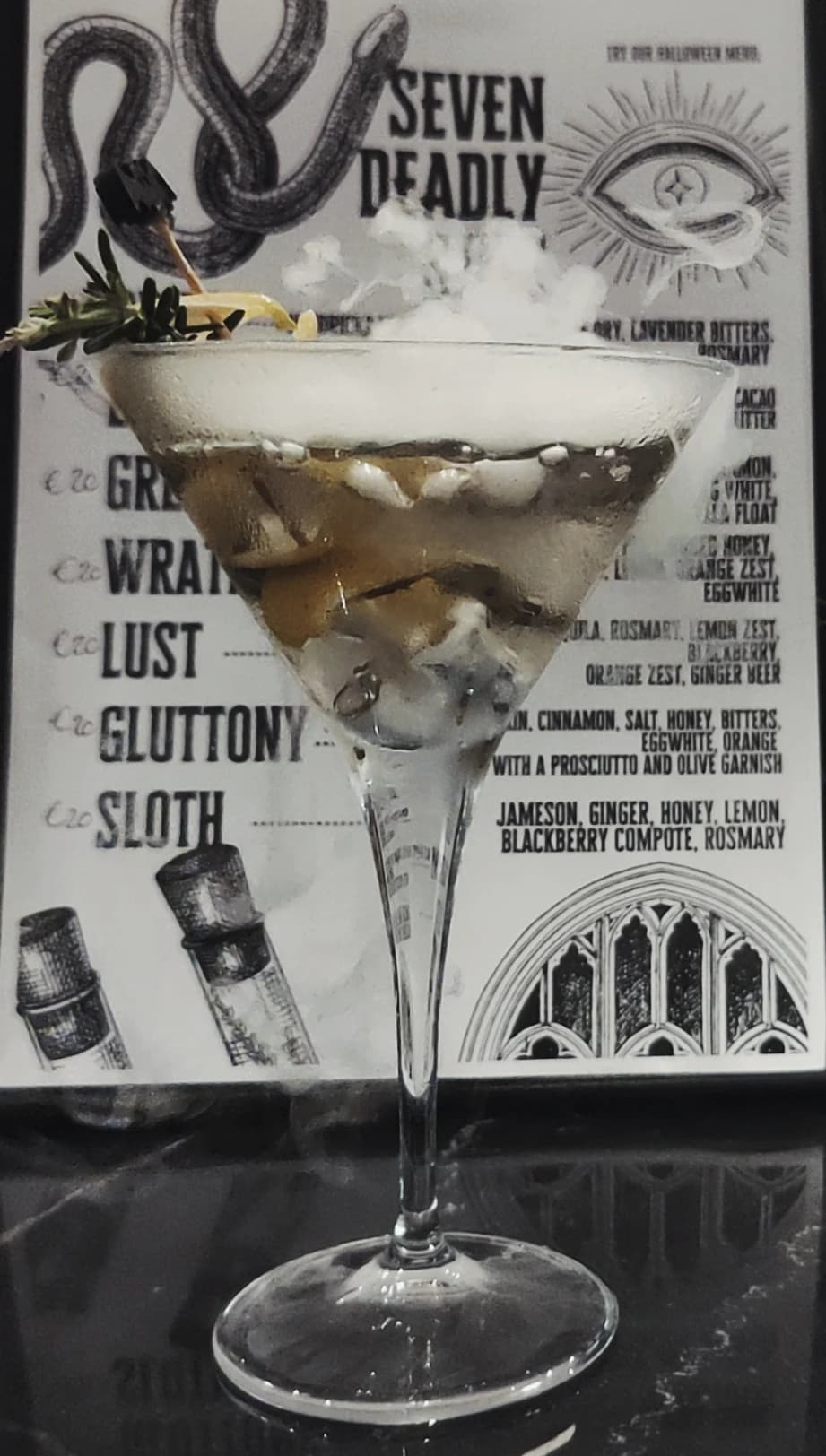 A classic martini with an olive, cocktail menu behind