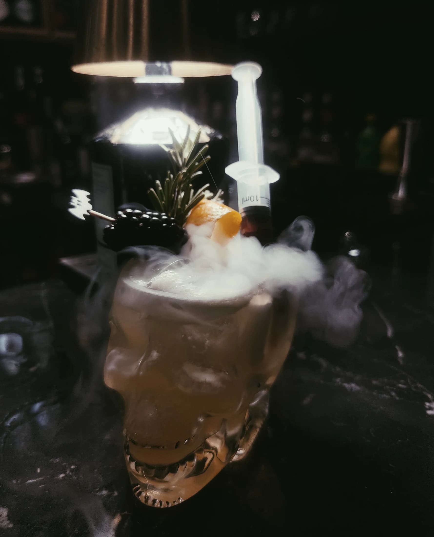 A smoked cocktail dramatically lit at the bar