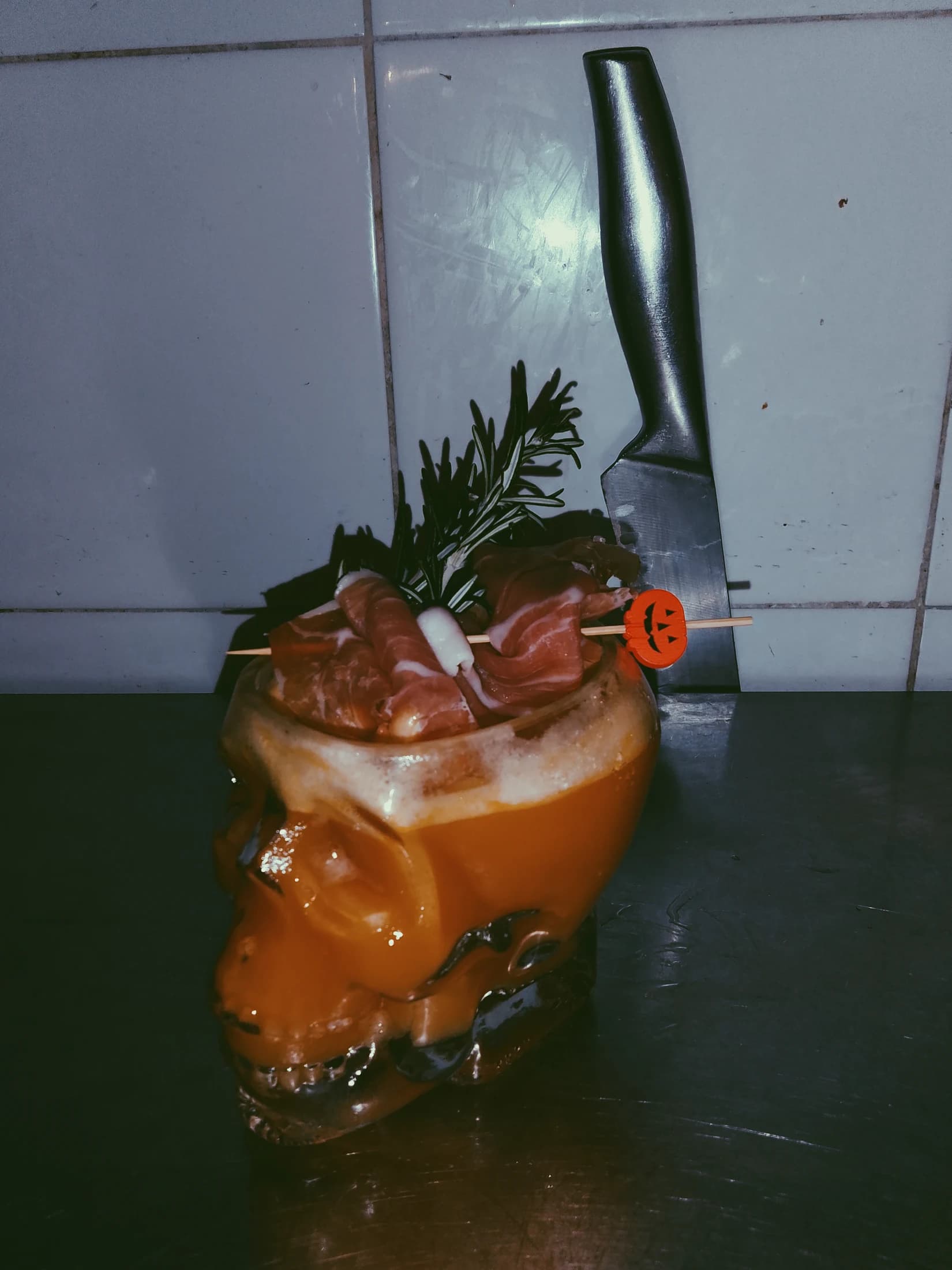 An orange cocktail garnished with fresh herbs